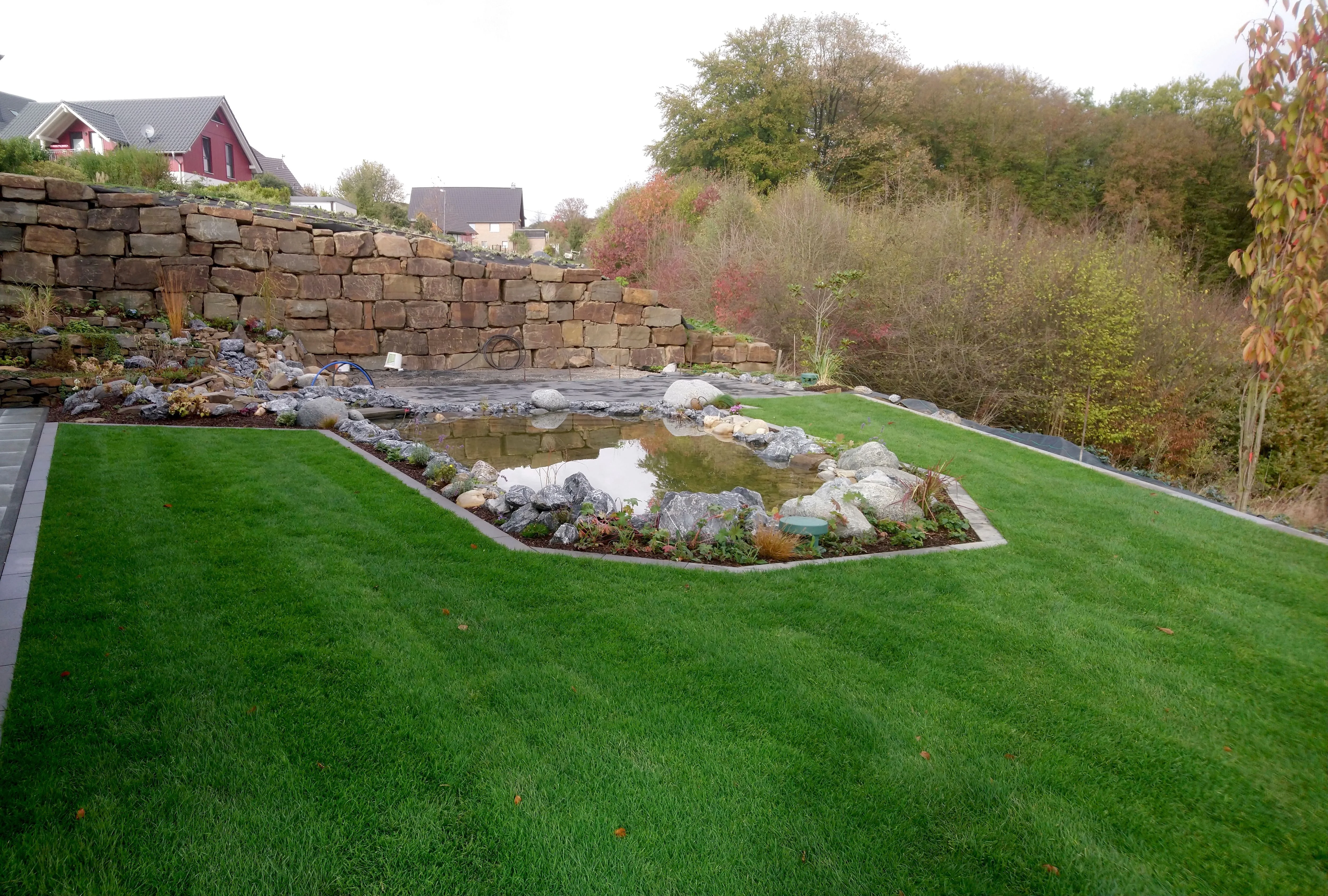 Natursteinmauer mit Teichanlage und Rollrasen
